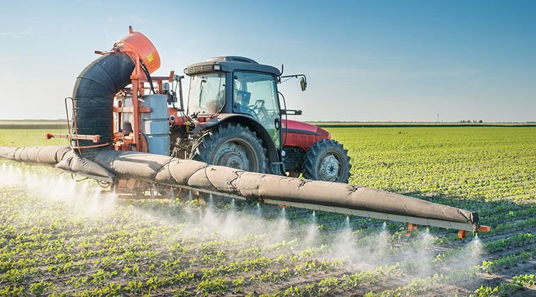 Tractor spraying on crops in a field